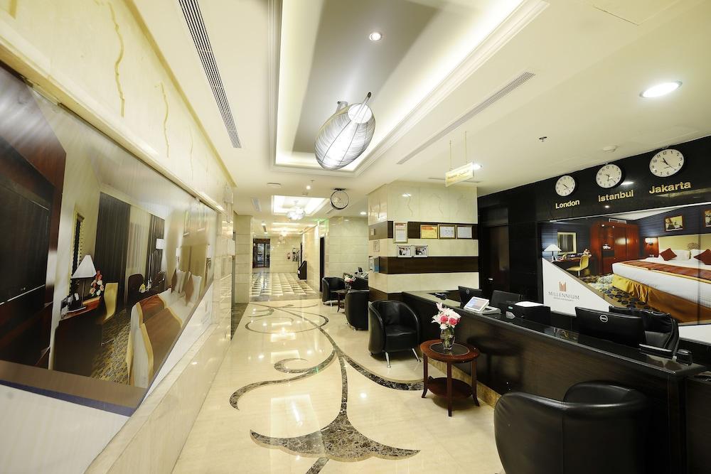 Al Aqeeq Madinah Hotel Medina Exteriör bild The photo shows the interior of a hotel lobby or reception area. It features a sleek, modern design with elegant marble flooring, decorative lighting fixtures on the ceiling, and a sophisticated color scheme. There are comfortable black seating areas