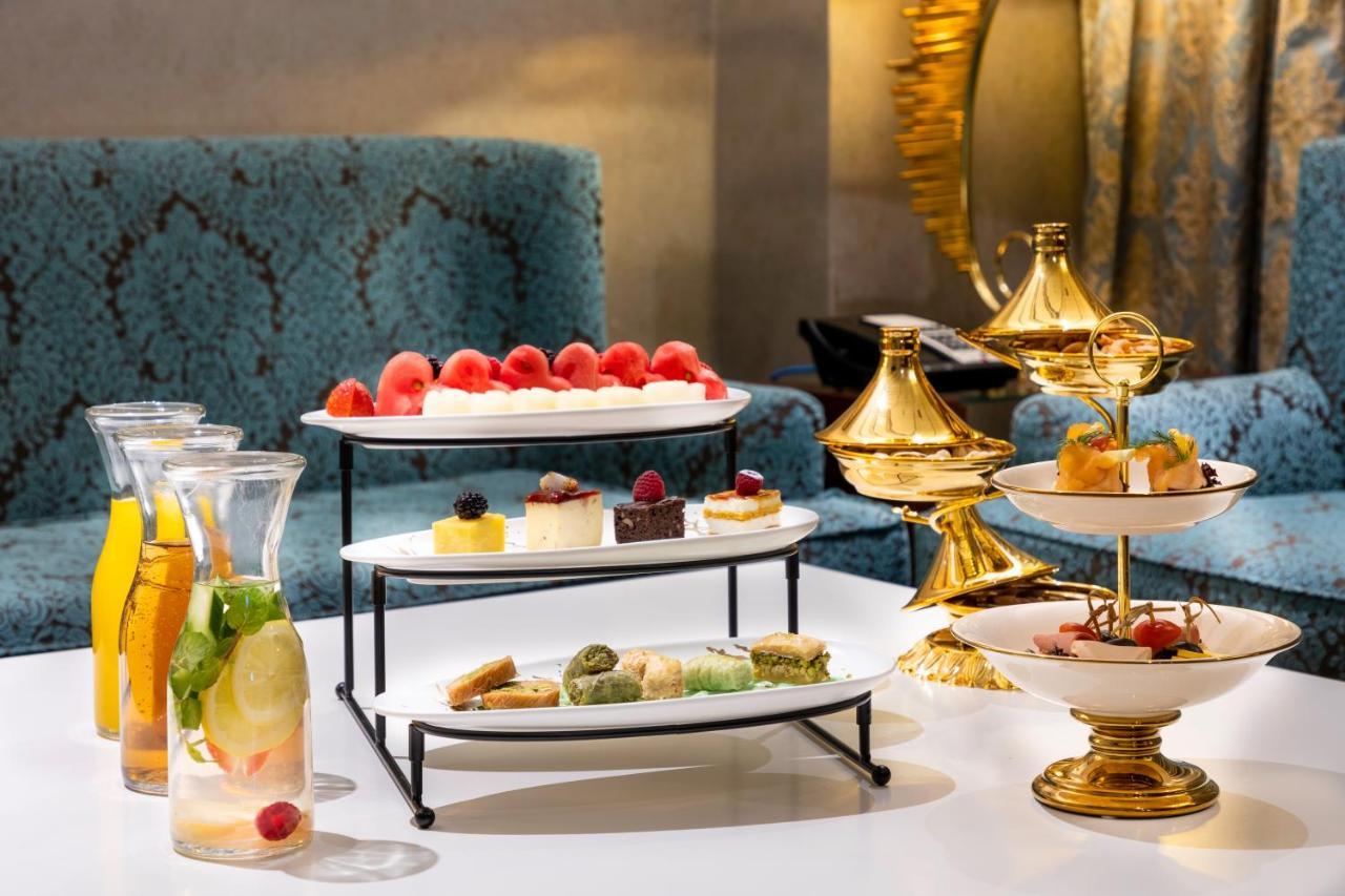 Al Aqeeq Madinah Hotel Medina Exteriör bild The photo displays an elegant dessert arrangement on a table. There are two levels of desserts: 

1. **Top Tier**: Features a selection of colorful sweets, including layers of cream or mousse desserts, garnished with fresh berries.
2. **Bottom Tier**