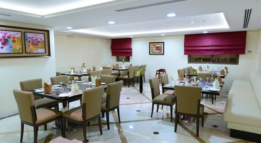 Al Aqeeq Madinah Hotel Medina Exteriör bild The photo shows a well-decorated restaurant interior. It features several tables arranged neatly throughout the space, each set with chairs and tableware, including plates, glasses, and napkins. The flooring is a polished stone surface with a stylish